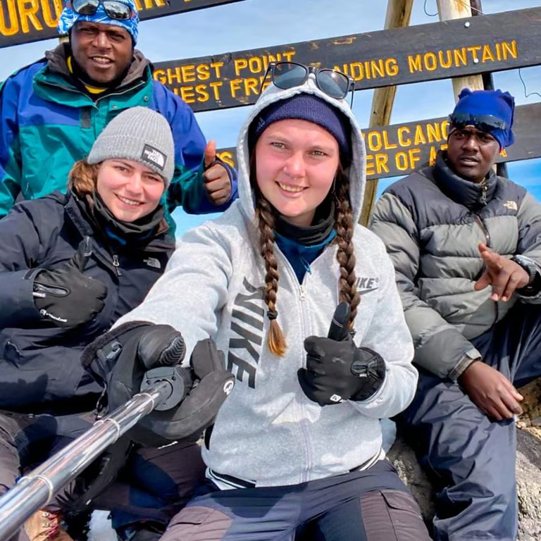 Climb Mount Kilimanjaro guide with climbers at Uhuru Peak summit